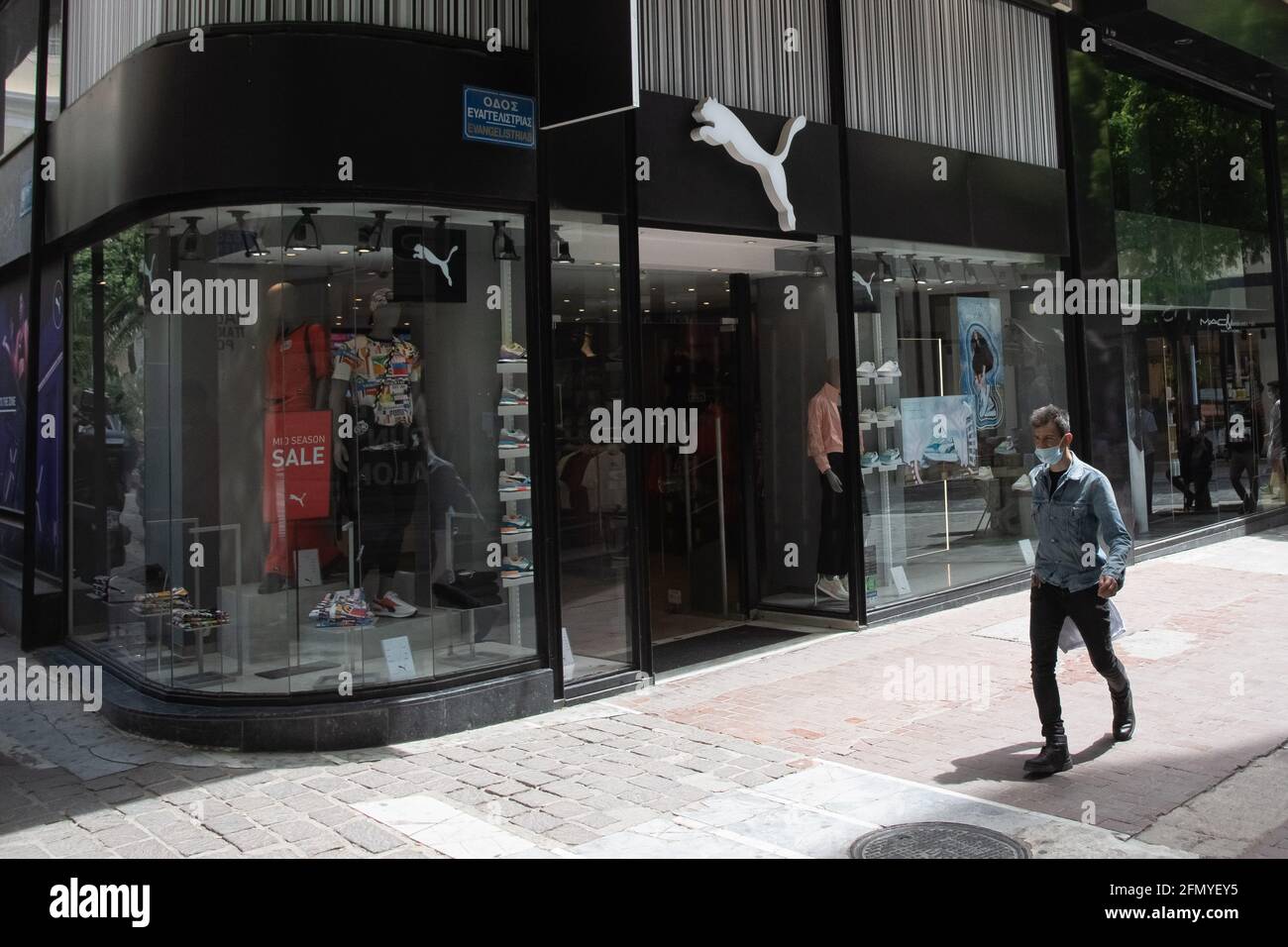 Athens, Greece. 12th May, 2021. A man wearing a face mask walks past a Puma  store
