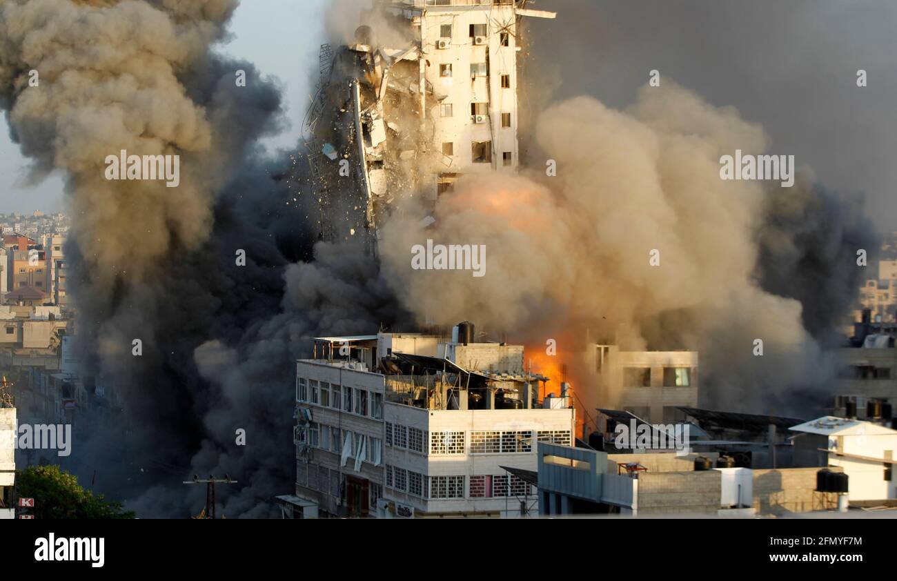 Gaza, Palestine. 12th May, 2021. Smoke and flames rise from a tower building destroyed by Israeli air strikes amid a flare-up of Israeli-Palestinian violence in Gaza CityIsrael carried out hundreds of air strikes in Gaza on Wednesday and Palestinian militants fired multiple rocket barrages at tel aviv and the southern city of Beersheba in the region's most intense hostilities in years. Credit: SOPA Images Limited/Alamy Live News Stock Photo