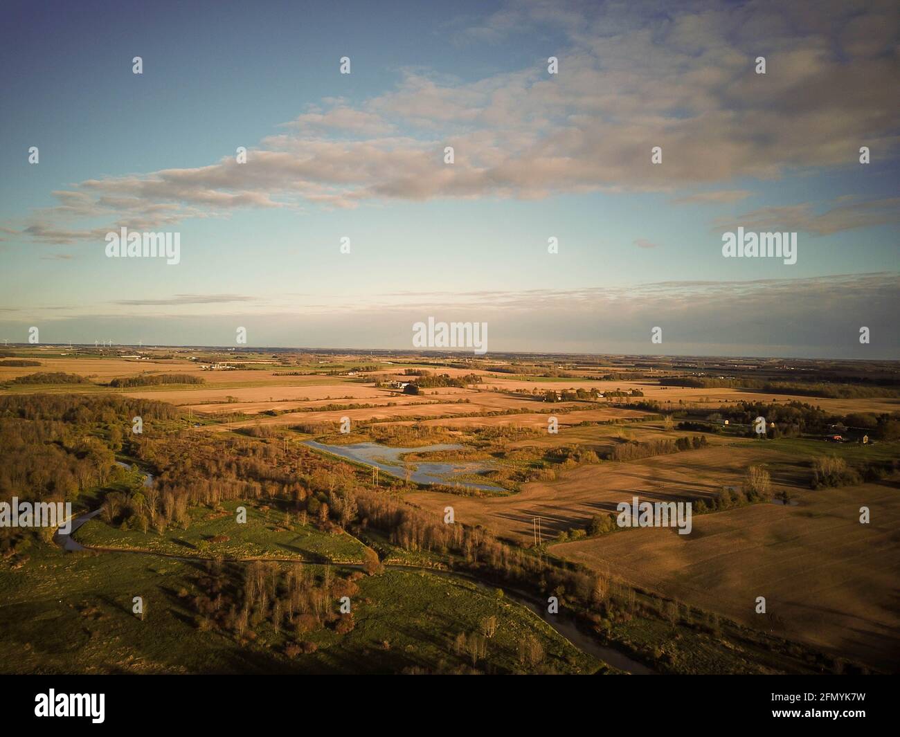 Aerial view of small river flowing through green marshy riparian ...