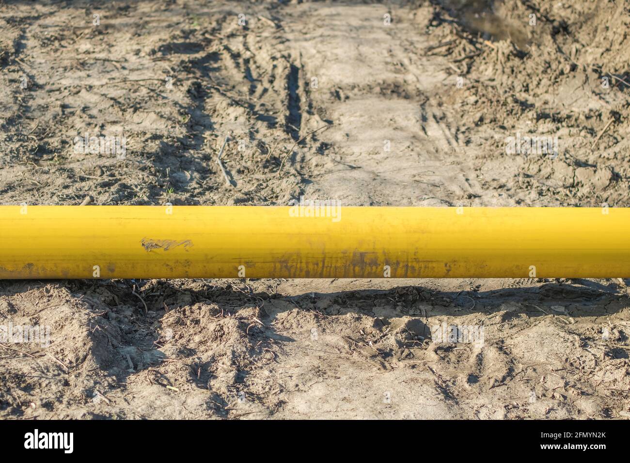 A dirty yellow pipe lies on the dry, trampled ground. Closeup Stock