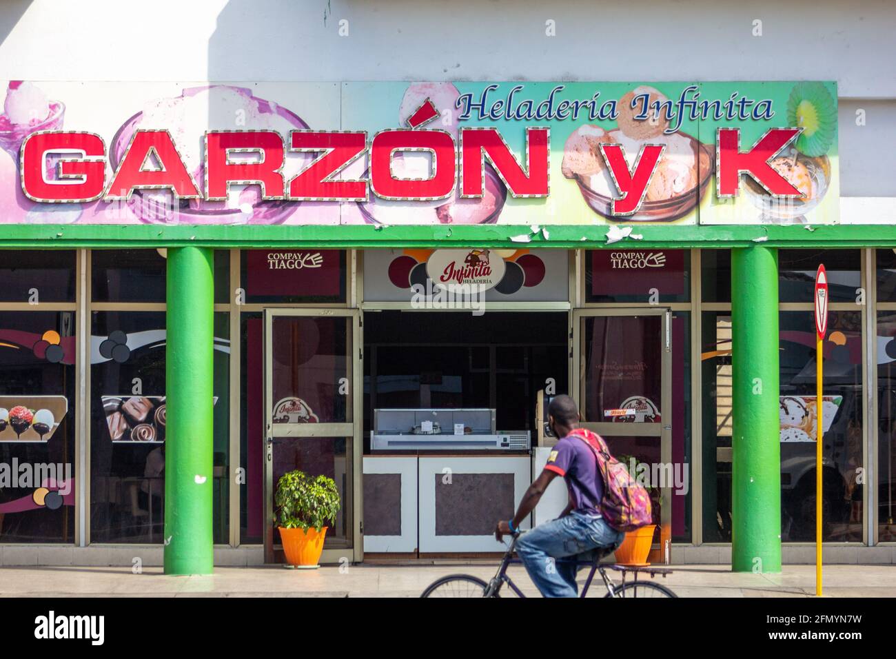 Ice-cream business in Garzon Avenue and K in Santiago de Cuba, Cuba. A man passes in a bike looking to the food exhibit. Stock Photo