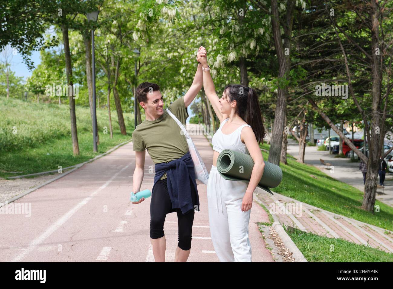Young sport couple slapping hands in a 'high-five' and laughing. Fitness outside. Stock Photo