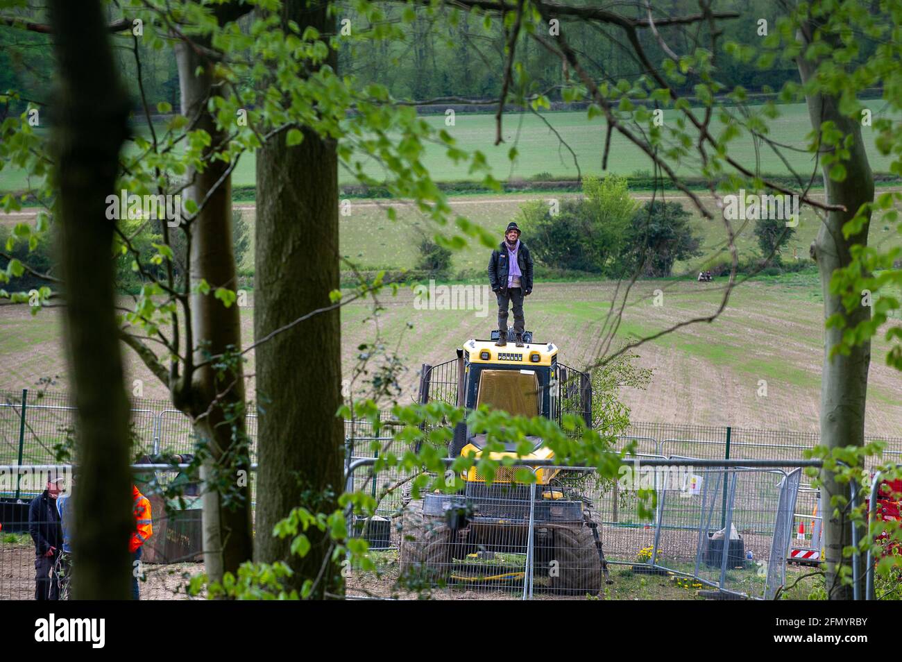 Aylesbury Vale, UK. 12th May, 2021. An anti HS2 protester covertly entered the heavily guarded HS2 compound at Jones Hill Wood today and occupied HS2 machinery to delay HS2 work. Thames Valley Police climbers removed the peaceful protester later this afternoon and arrested the young man. Meanwhile HS2 tree fellers were felling a large number of mature beech trees in the ancient woodland today despite the licence granted to HS2 from Natural England allegedly having expired. Rare Barbastelle bats are known to roost in the woods. Credit: Maureen McLean/Alamy Live News Stock Photo