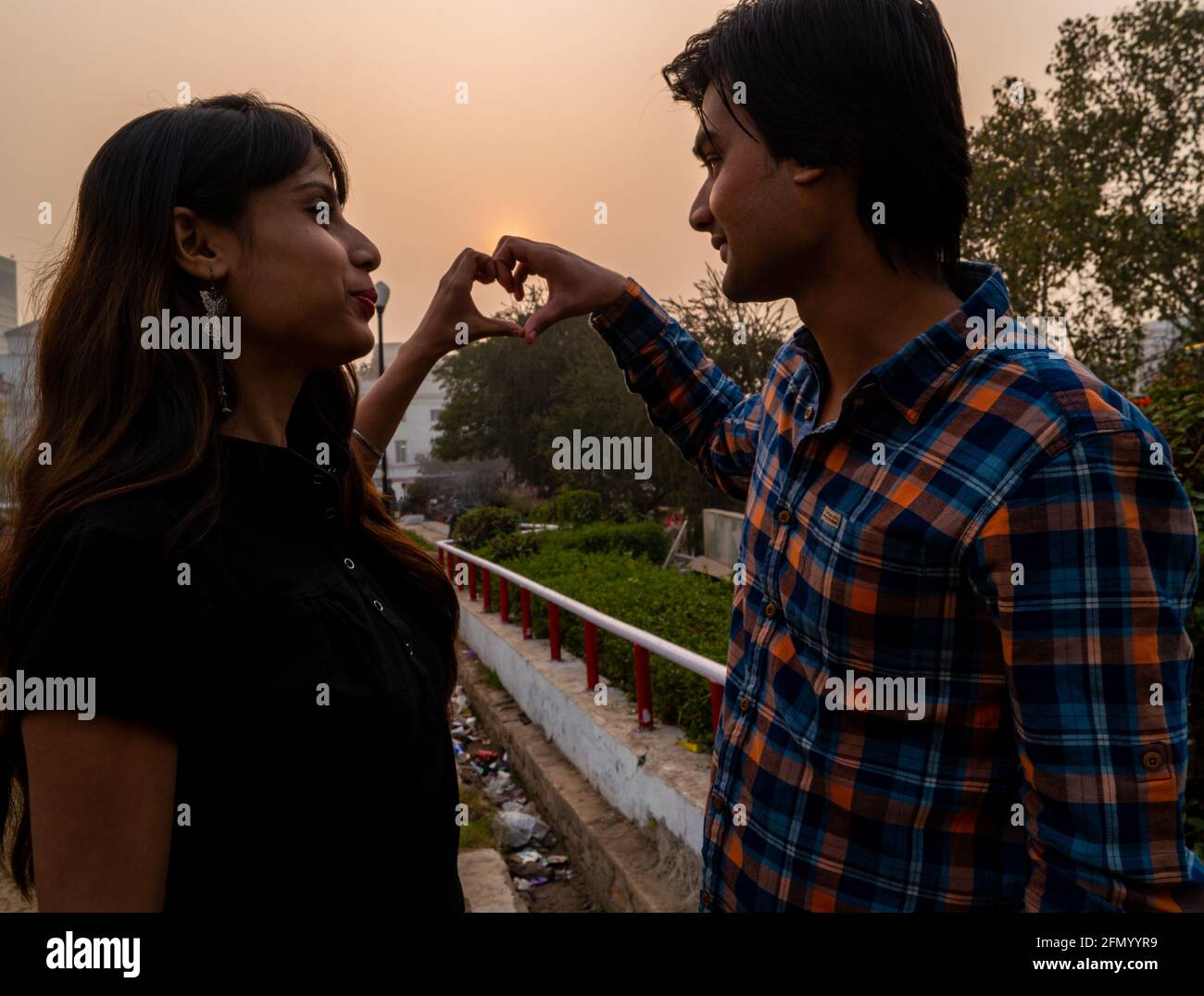 Beautiful Indian couple making a heart with their hands and looking at ...