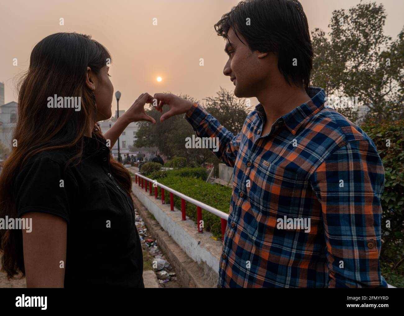 Beautiful Indian couple making a heart with their hands and looking at ...