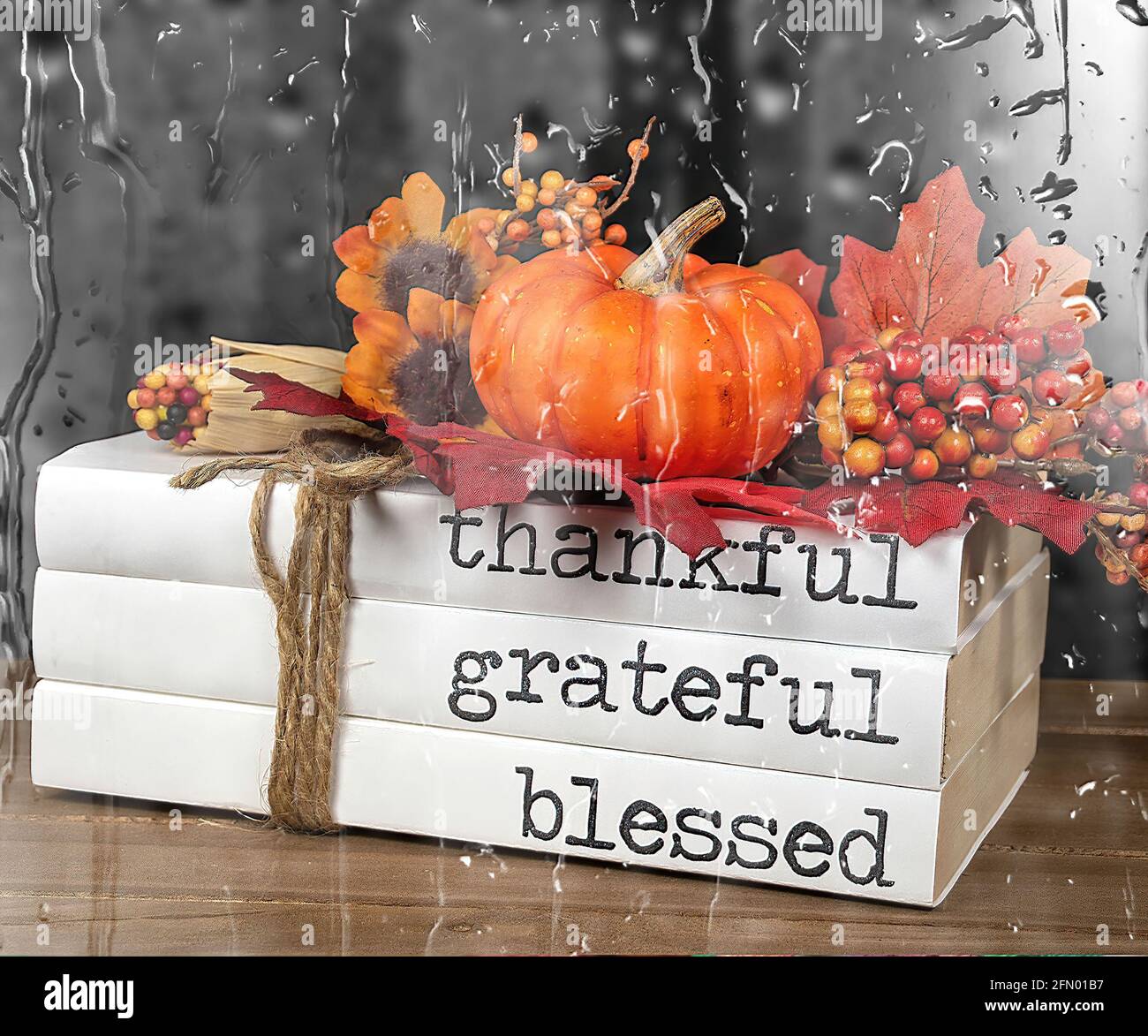Stack of books with autumn pumpkin and Thanksgiving text tied with string and raindrop overlay Stock Photo