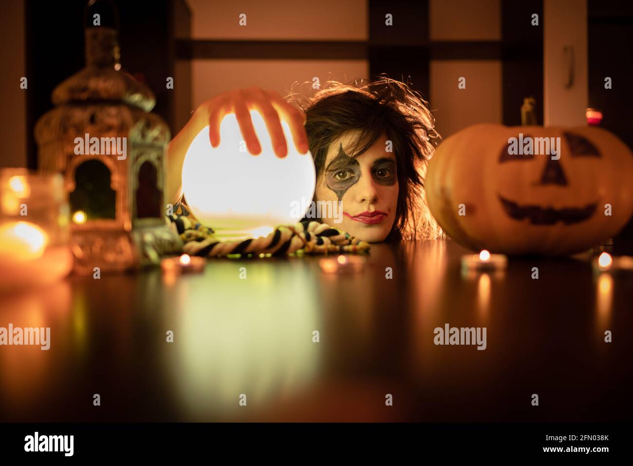 Halloween Witch with pumpkin and magic lights. Young and funny girl with halloween make up and costume ready for party. Stock Photo