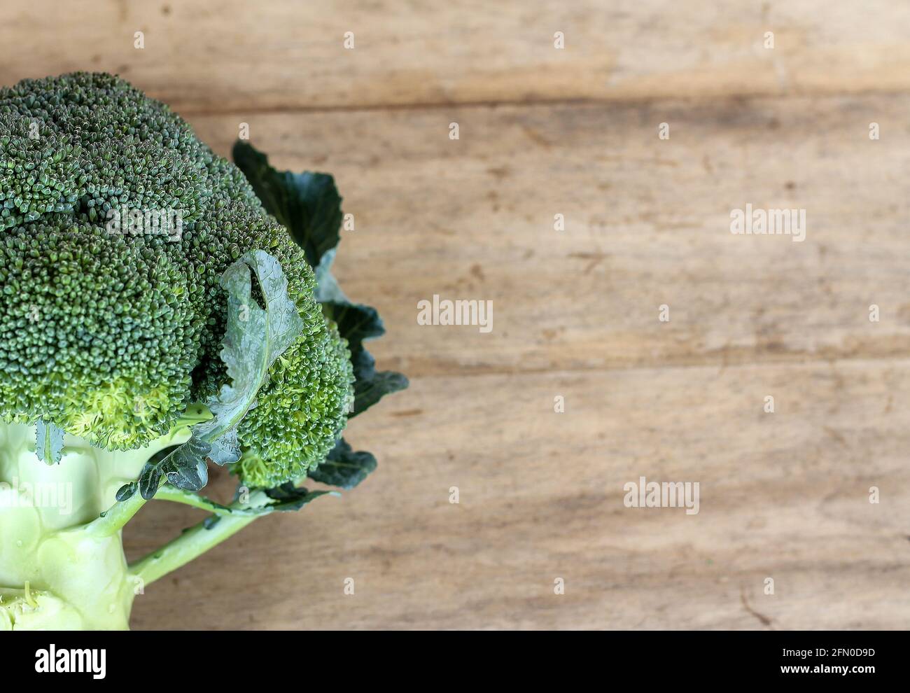 Green broccoli on a wooden table top leaves space for text messages. Stock Photo