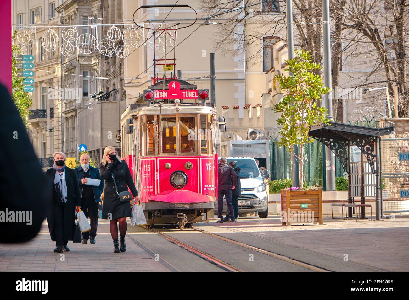 Most well known taksim square during morning with red, vintage and retro style tram in istiklal street and many tourists with medical masks. Stock Photo