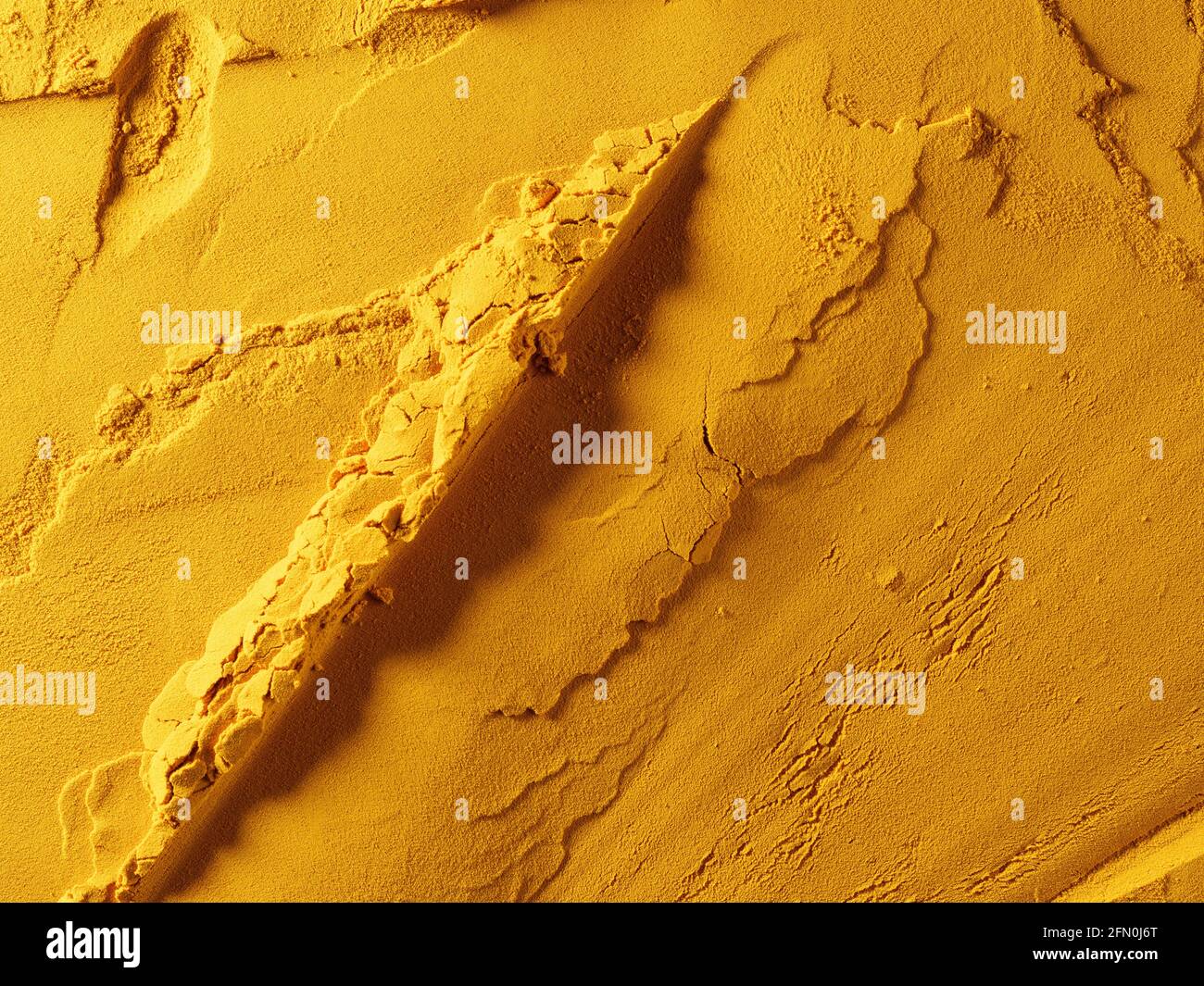 Yellow powder of grated turmeric with texture, food background. View ...