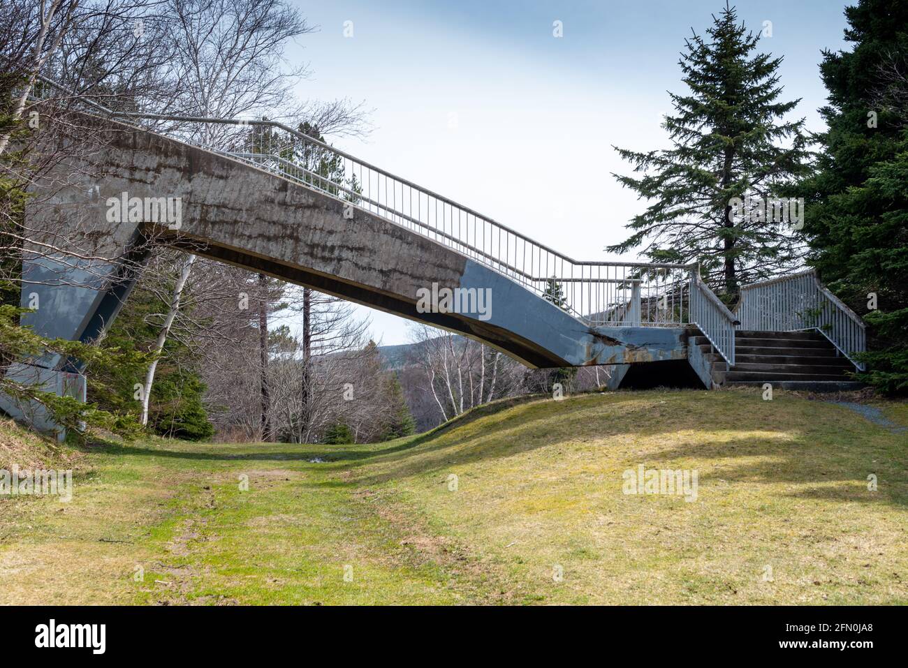 A vintage concrete pathway cantilever bridge spanning over a path in a park. Stock Photo