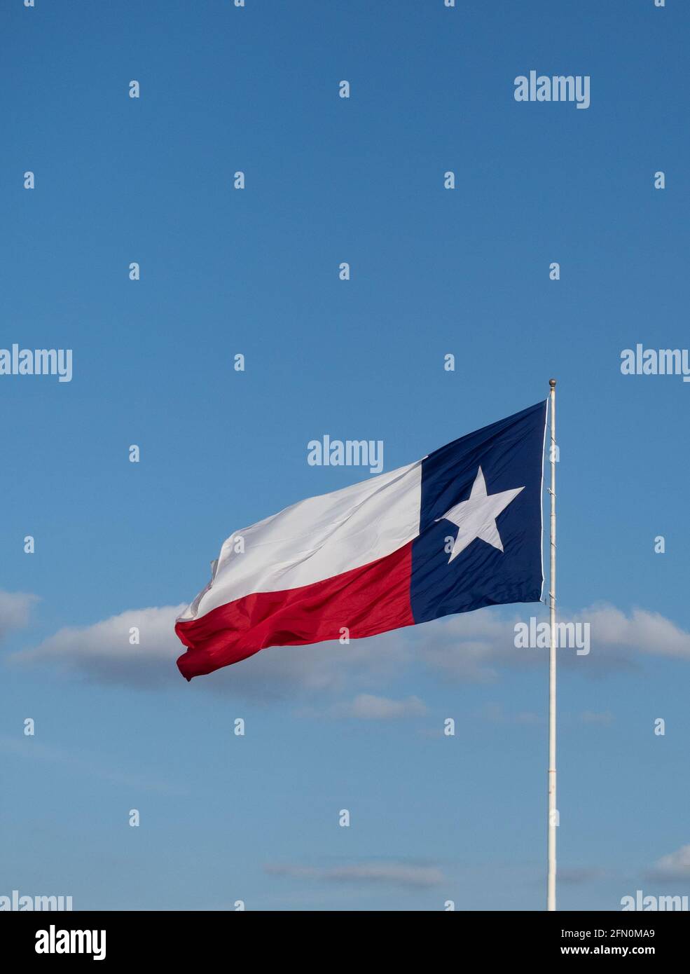 Texas Lone Star state flag with white star on blue background unfurled on a windy day. Blue sky with clouds in the background. Image has copy space. Stock Photo