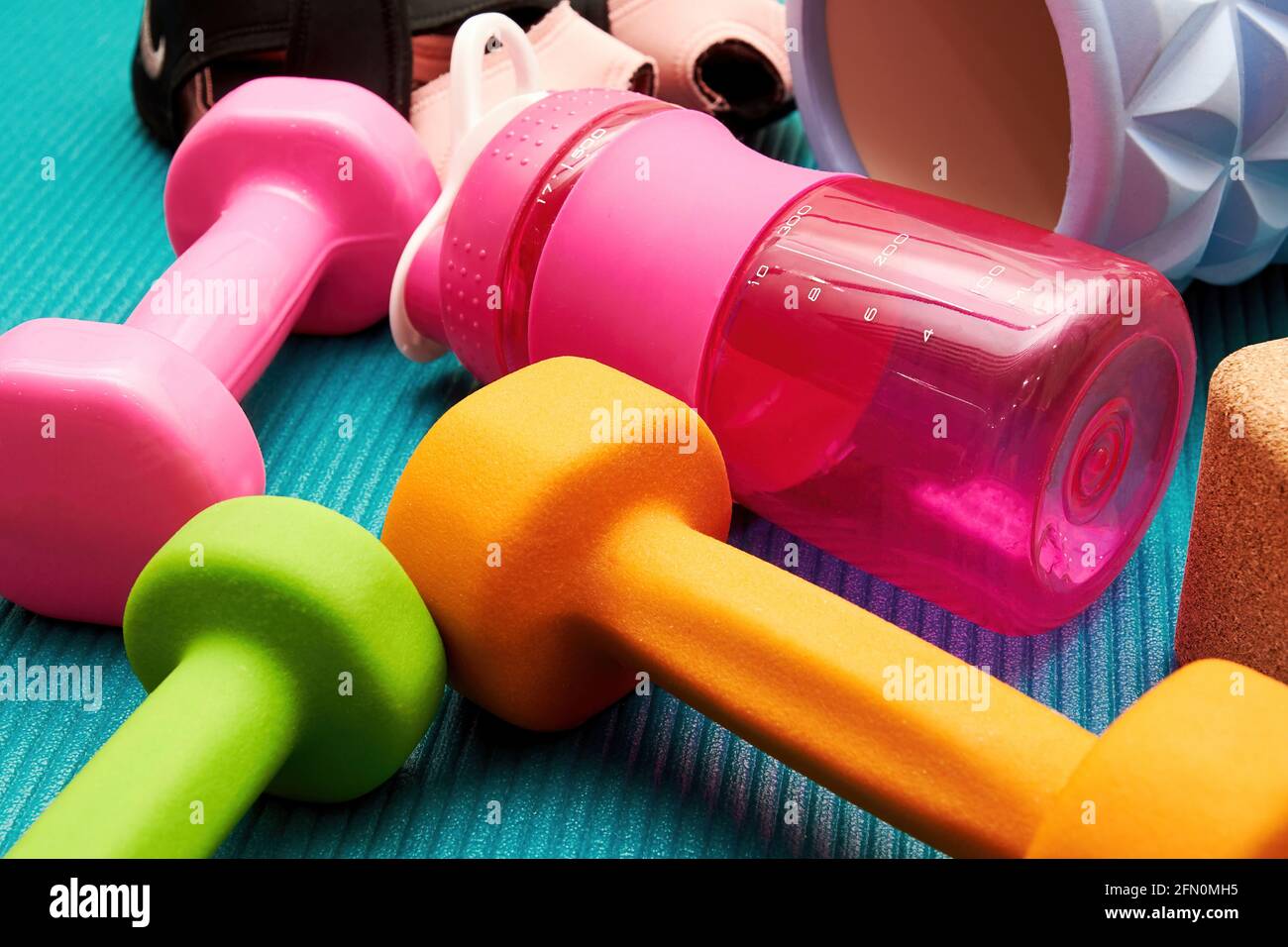 Fitness accessories, sneakers, dumbbell, roller, bottle, sports brick on the mat. Gym equipments and healthy lifestyle backgrounds Stock Photo