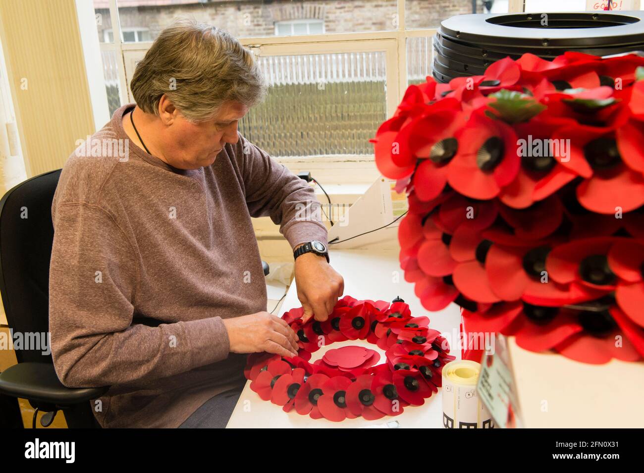 William Sellick making a poppy wreath at, The Royal British Legion's Poppy Factory, 20 Petersham Road, Richmond, London, UK. The Poppy Factory employs ex-service personnel to makes poppies, remembrance crosses, sprays and wreaths for The Royal British Legion’s annual Appeal and Remembrance Day. The Poppy Factory is also responsible for planting and hosting The Field of Remembrance at Westminster Abbey. The Royal British Legion's Poppy Factory, 20 Petersham Road, London, UK.  16 Oct 2013 Stock Photo