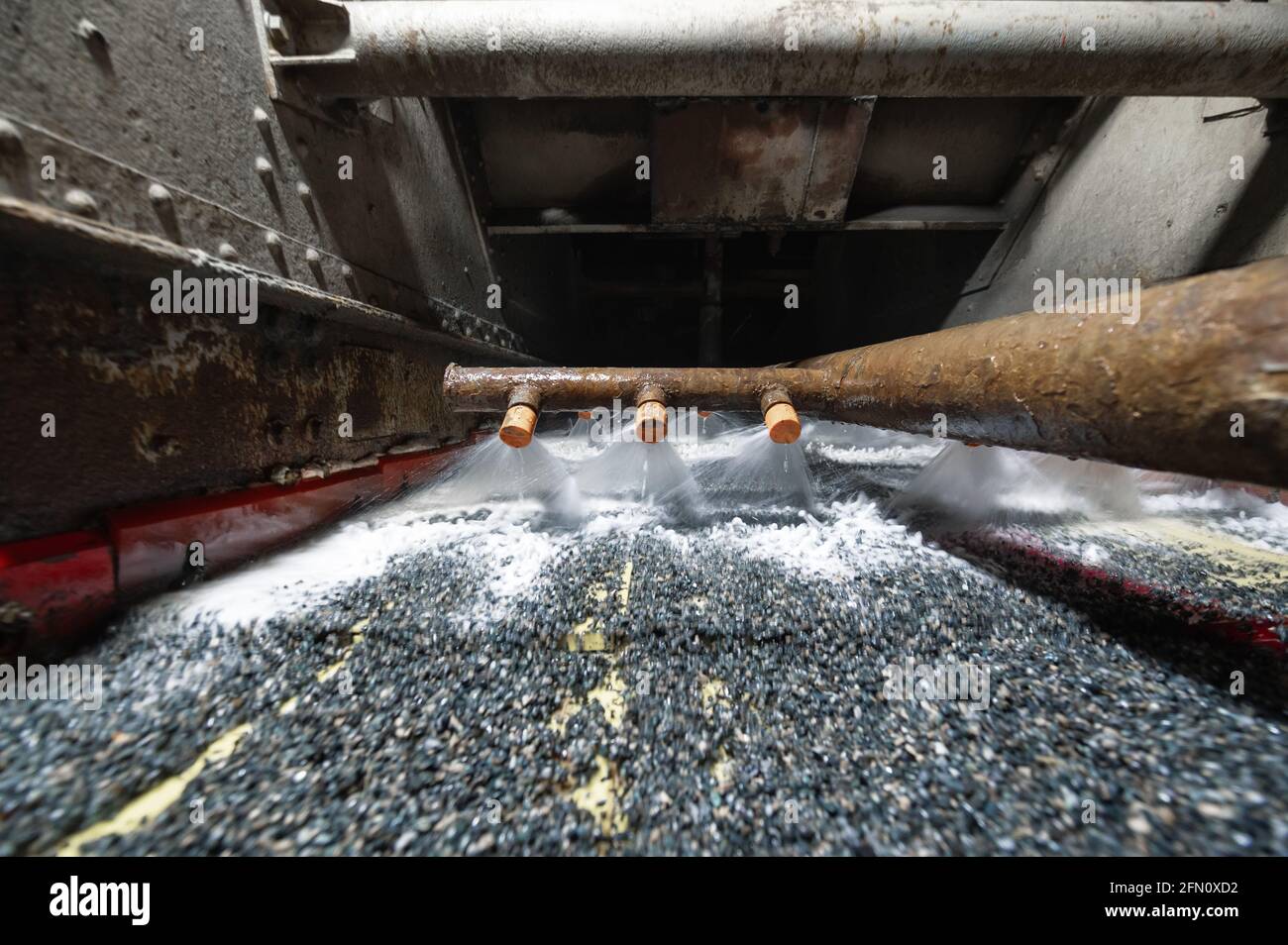 Vibrating screen, ore washing with liquid. Lots of small stones on the surface of the sieve Stock Photo