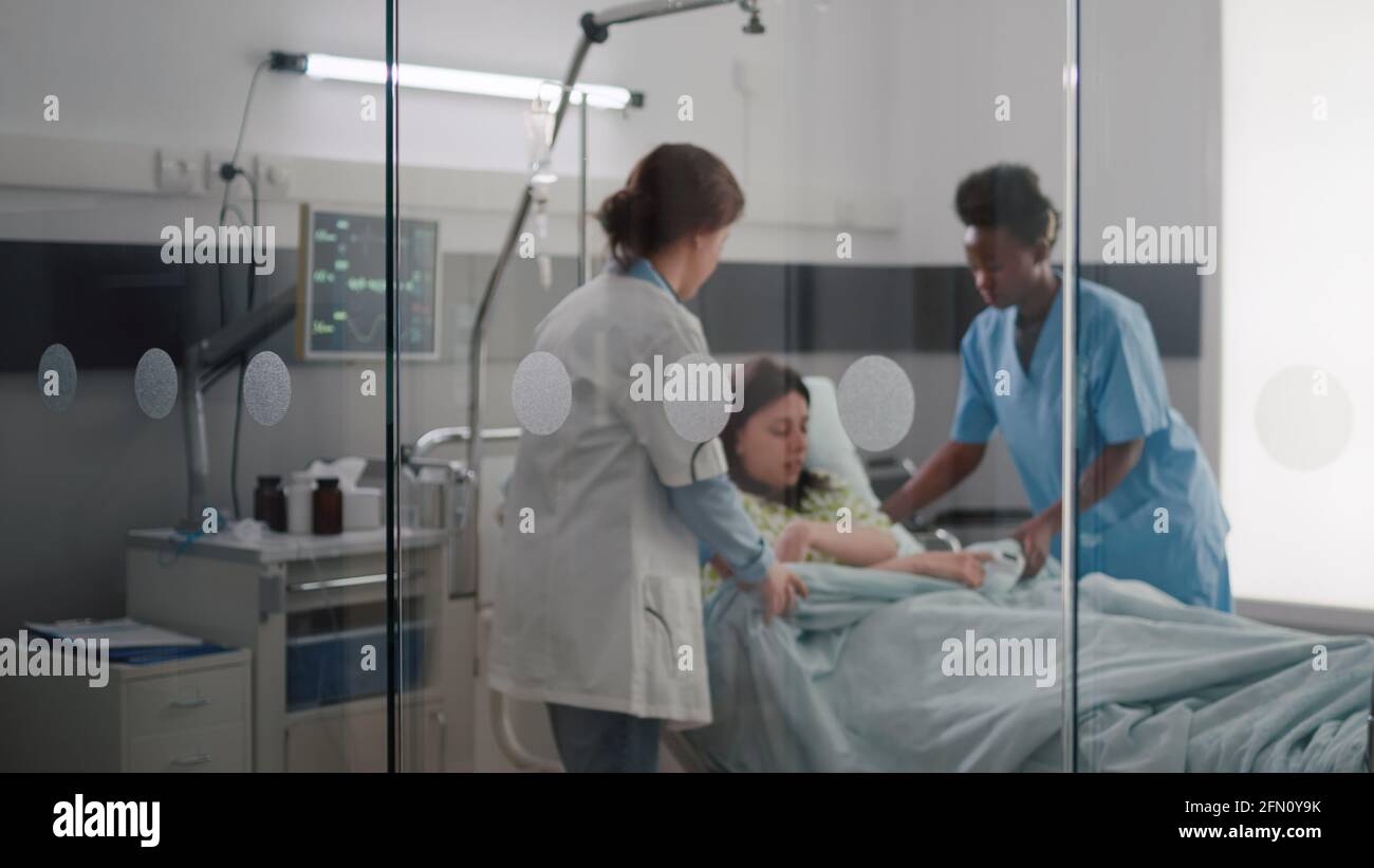 Medical team helping patient putting into bed during sickness emergency ...