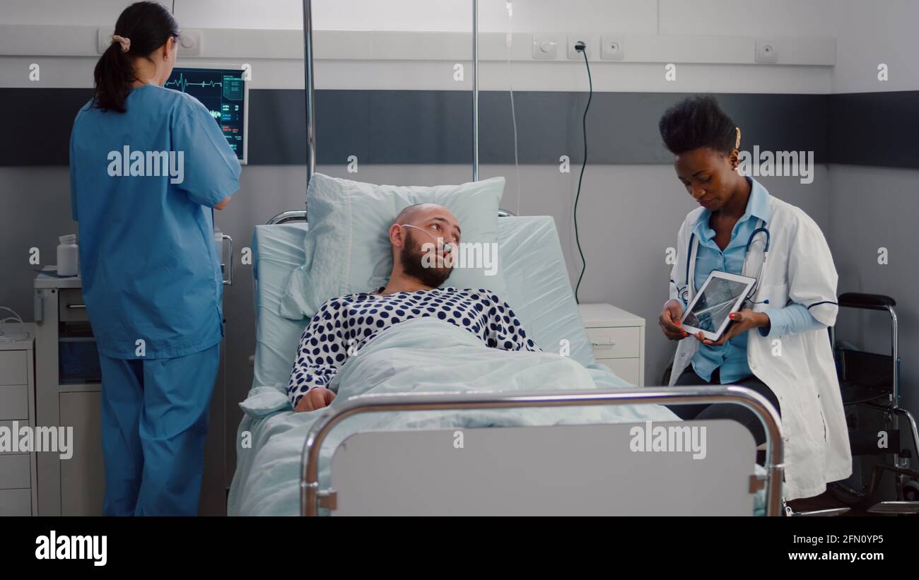 Practitioner black doctor explaining bones radiography to sick man ...