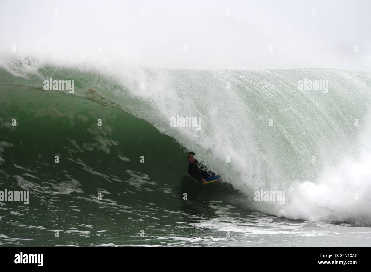 Surfing in Cornwall. A bodyboarder rides deep inside the tube of a