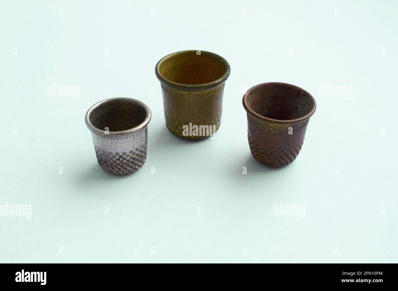 Three vintage thimbles stand in a row isolated on a colored background Stock Photo Alamy