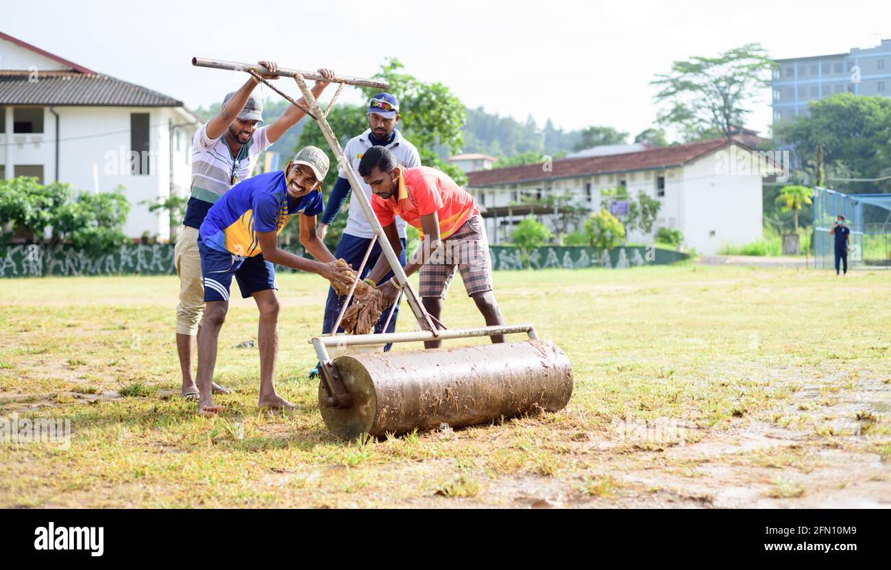 Galle, Sri Lanka - 04 17 2021: Players and staff preparing cricket pitch and the ground after heavy rain. removing excess water and mud while roller u Stock Photo