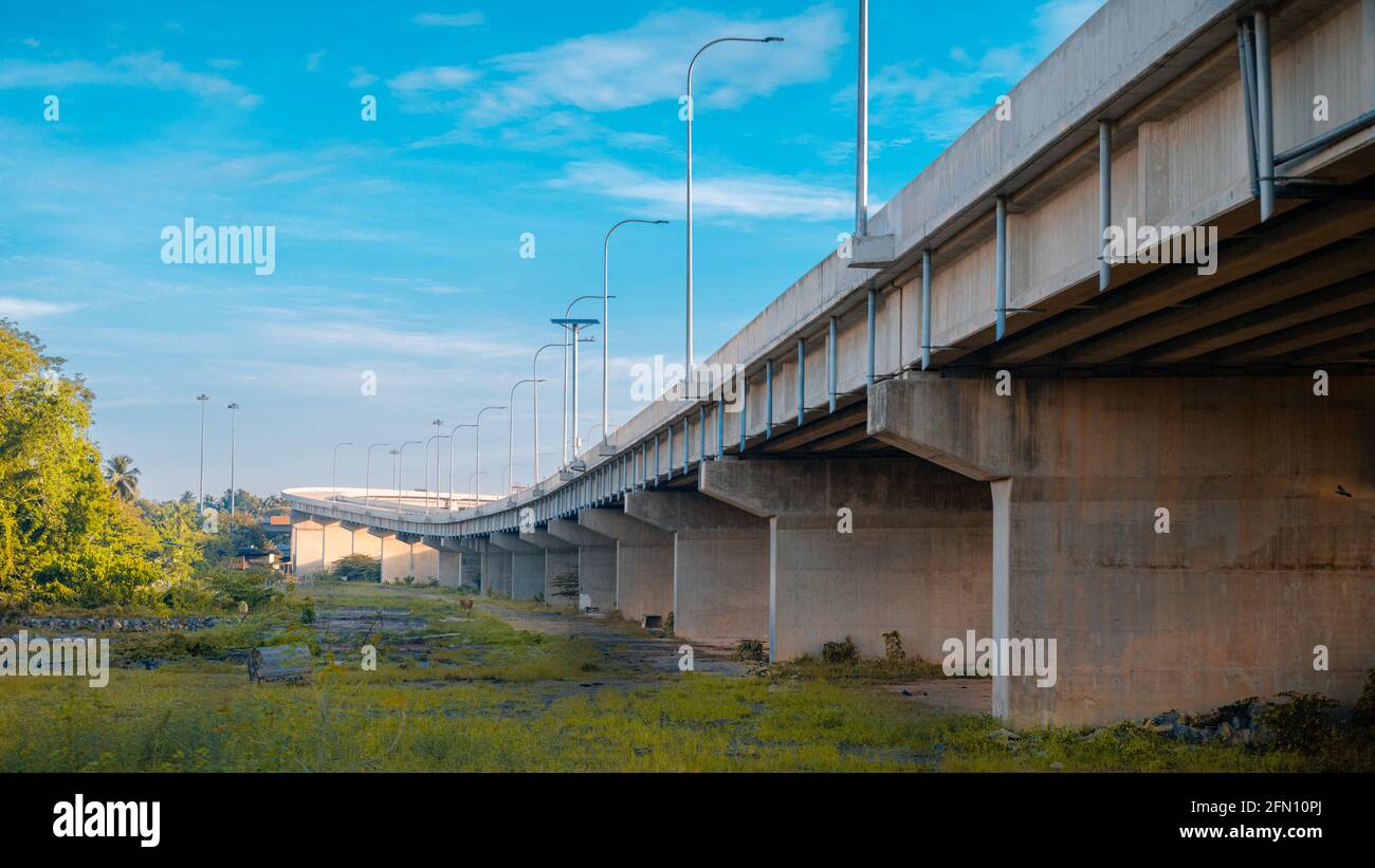Underneath the elevated Expressway concrete structure, greenery, and clear blue skies landscape view. Stock Photo