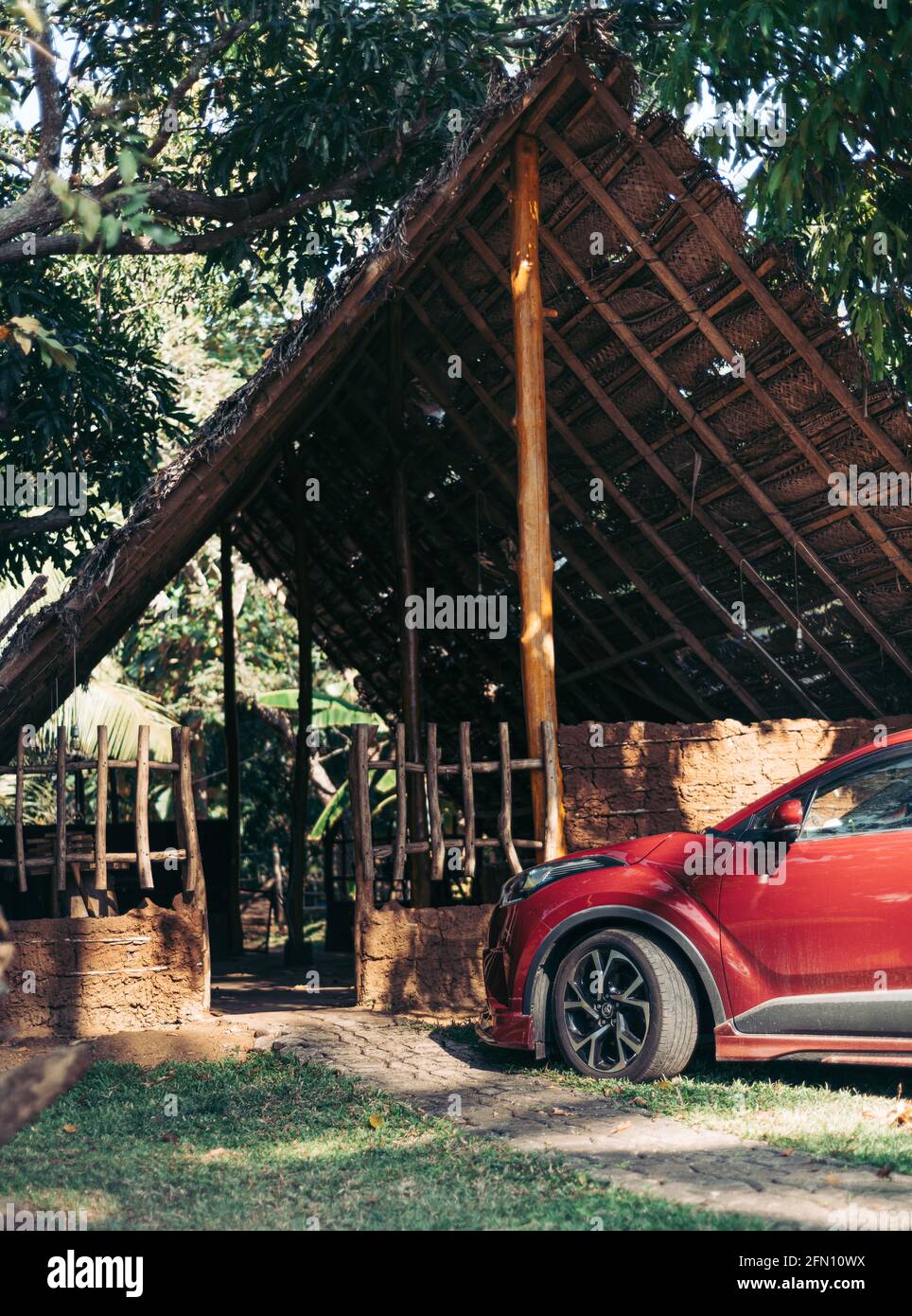 A luxury vehicle parked in front of a thatched village hut, Stock Photo