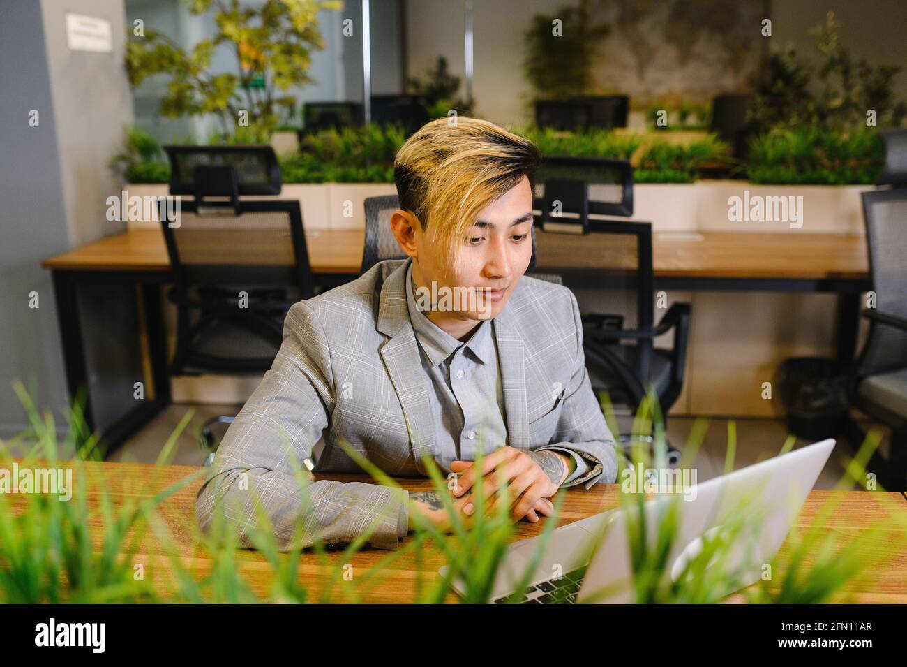a young Asian manager is working in an office with a laptop. Modern work space, coworking Stock Photo