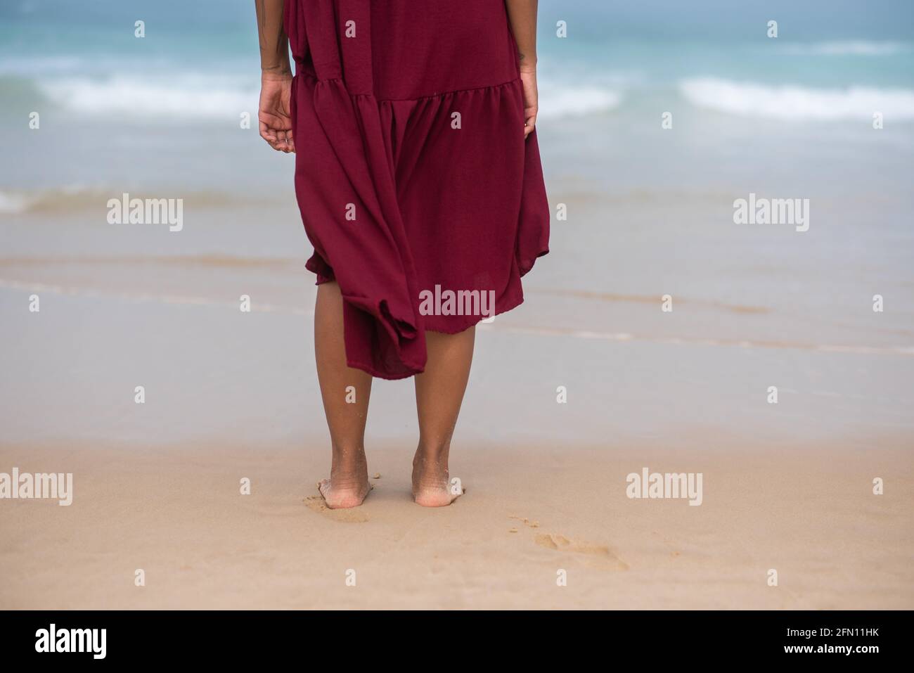Woman seen standing with water from ocean in background Stock Photo