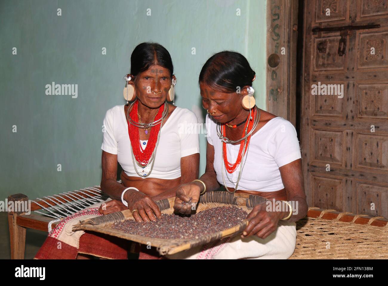 Tribal women with winnowing pan with round wooden plugs in huge ear lobes. Characteristic tattoo mark down the middle of the forehead. LANJIA SAORA TR Stock Photo