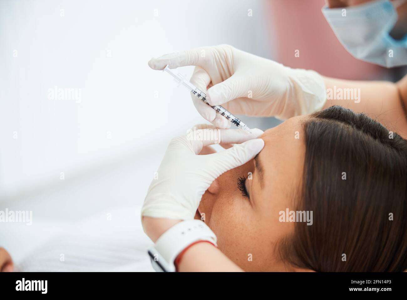 Woman getting a dermal filler injection into the glabellar line Stock