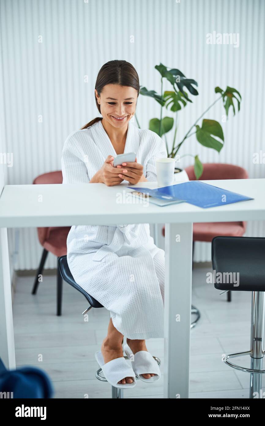 Spa client in a waffle weave bathrobe using her gadget Stock Photo