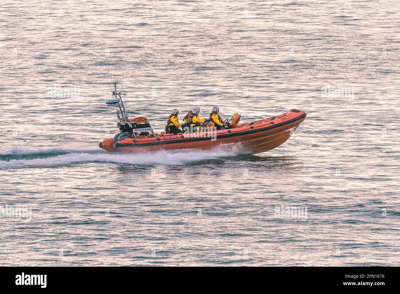 The RNLI Gladys Mildred, Newquay’s Atlantic 85 lifeboat responding to an emergency callout at the end of the day in Fistral Bay in Cornwall. Stock Photo