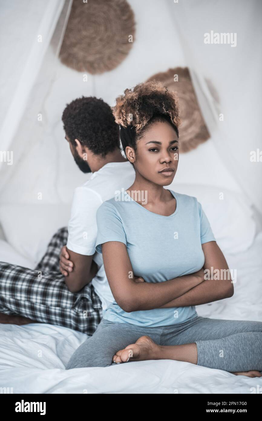 Angry woman sitting with back to her husband Stock Photo