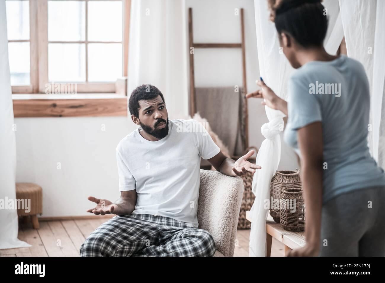 Indignant man sitting and wife standing with her back Stock Photo