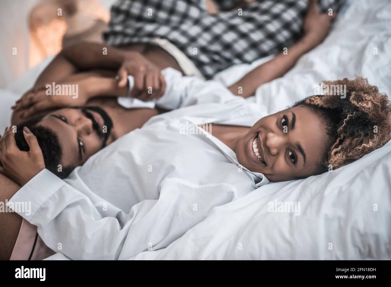 Joyful african american woman hugging husband on bed Stock Photo - Alamy