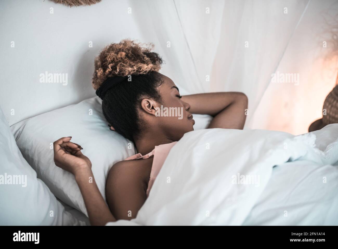 Dark-skinned woman sound asleep in white bed Stock Photo