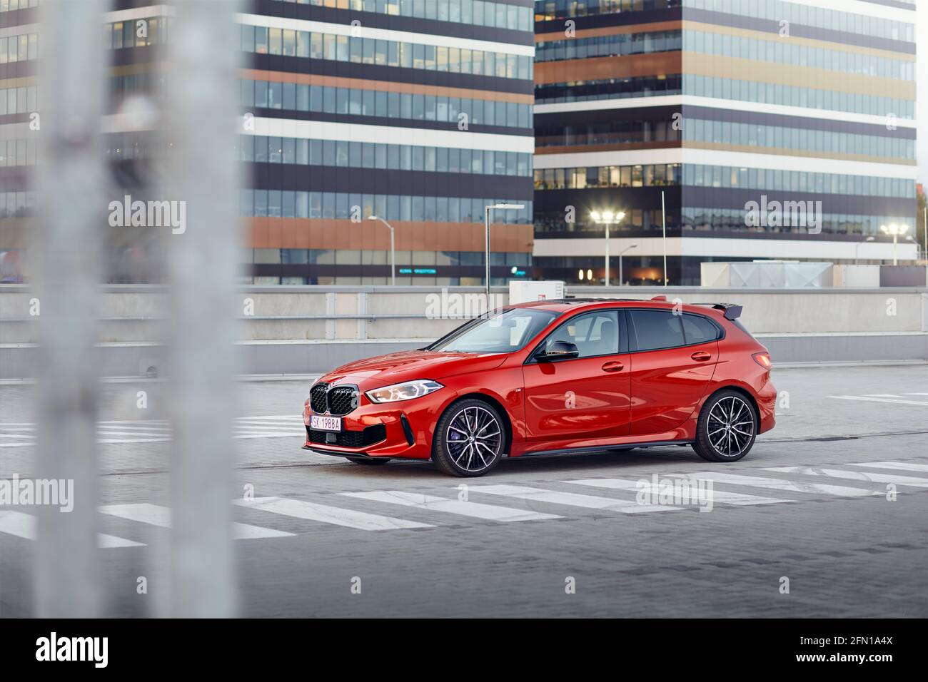 Red BMW M135i in the parking lot in front of the office buildings. Model F40, produced from 2019. 306 hp engine, acceleration 0-100 km / h: 4.8 s. Kat Stock Photo