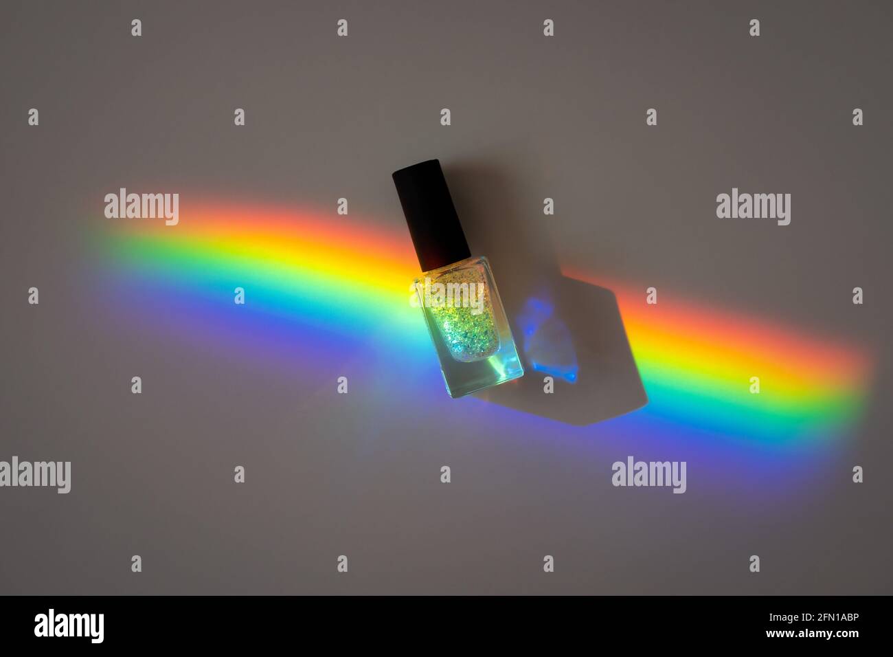Holographic Nailpolish in a prism rainbow line on a grey paper Stock Photo