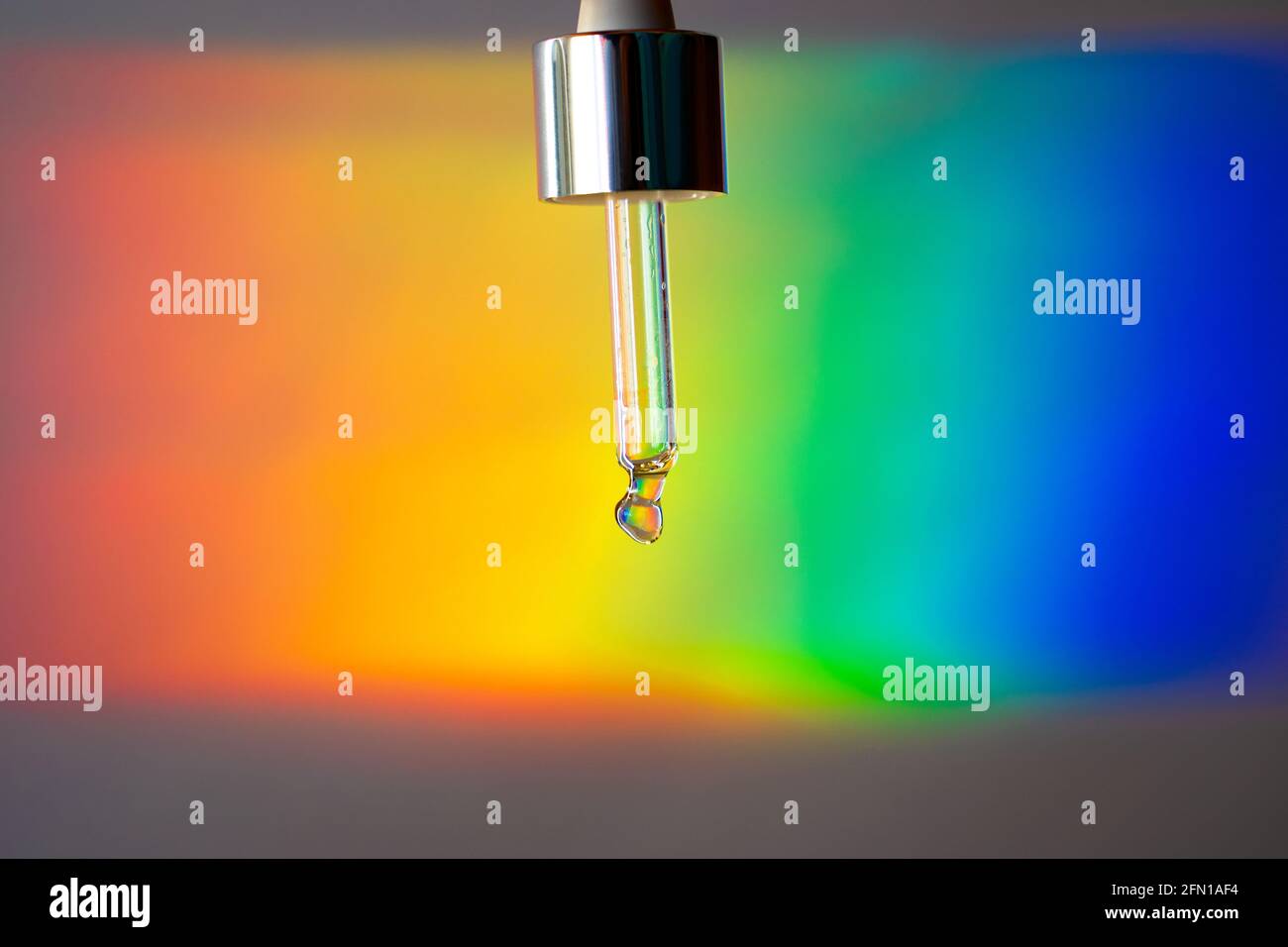 A Glass dropper on a prism rainbow background. Futuristic beauty Stock Photo