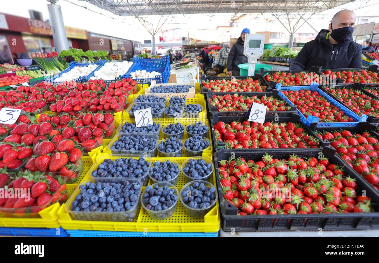 Man with face mask sell blueberries and strawberries at a farmer’s market in Sofia, Bulgaria on april 22, 2021 Stock Photo