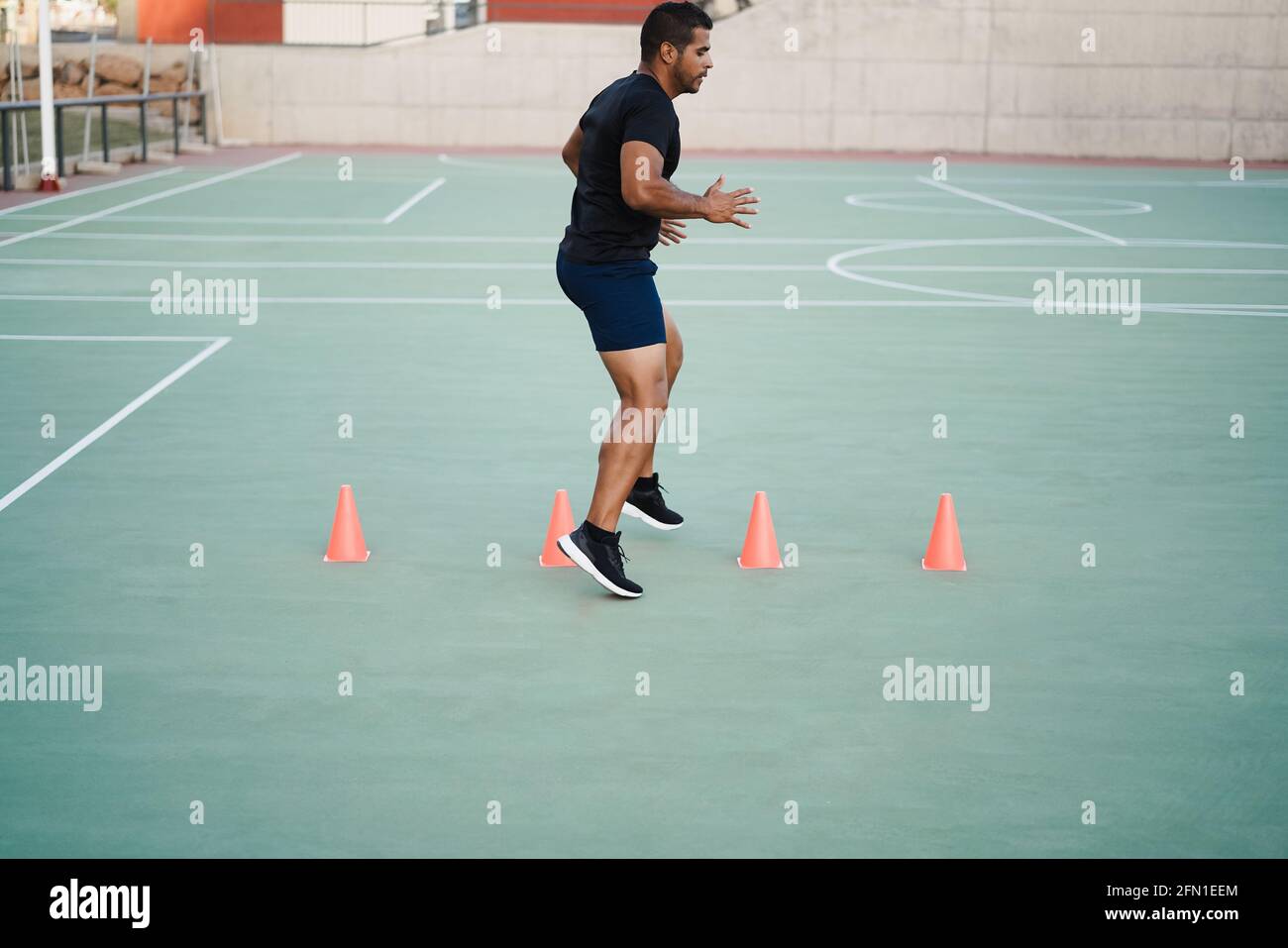 Hispanic man doing speed and agility cone drills workout session outdoors - Focus on man face Stock Photo