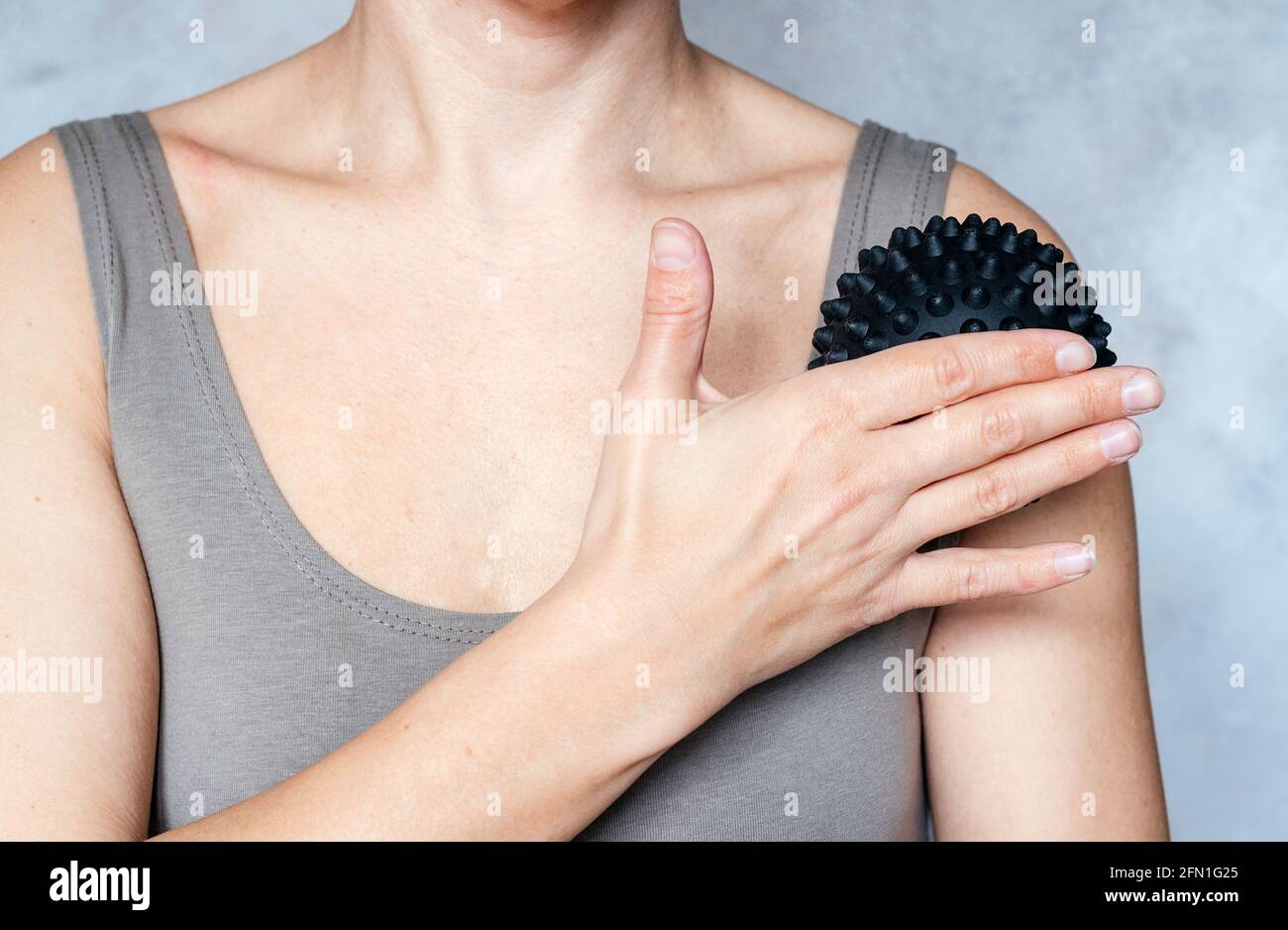 A woman massages her arm with spiky trigger point ball, muscle pain
