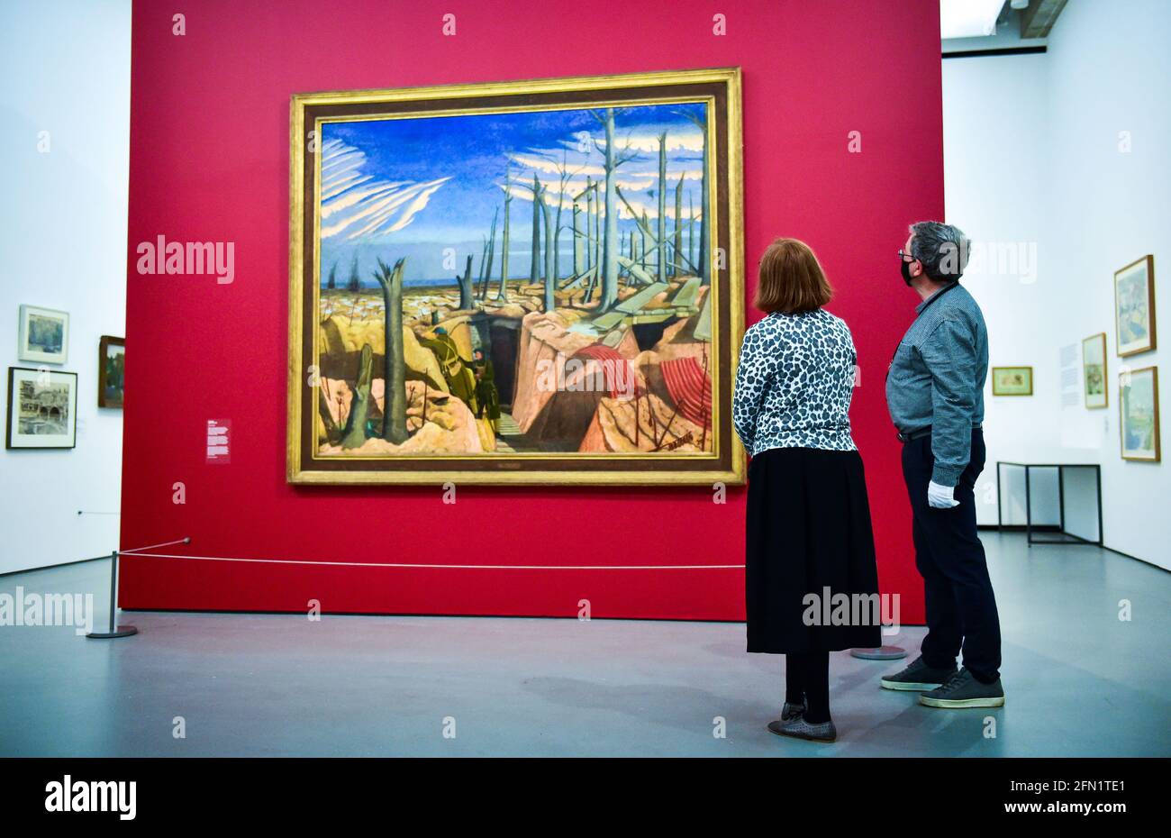 Brighton UK 13th May 2021 - Co-curators Sara Cooper and Andy Friend with the famous Oppy Wood painting (on loan from the Imperial War Museum ) by John Nash at the Towner Eastbourne as they prepare to present the first major exhibition of John Nash works in 50 years, as galleries across England reopen after lockdown. Towner Eastbourne presents the most comprehensive exhibition of work in over 50 years by John Nash, one of the most versatile and prolific artists of the 20th century. Credit: Simon Dack/Alamy Live News Stock Photo