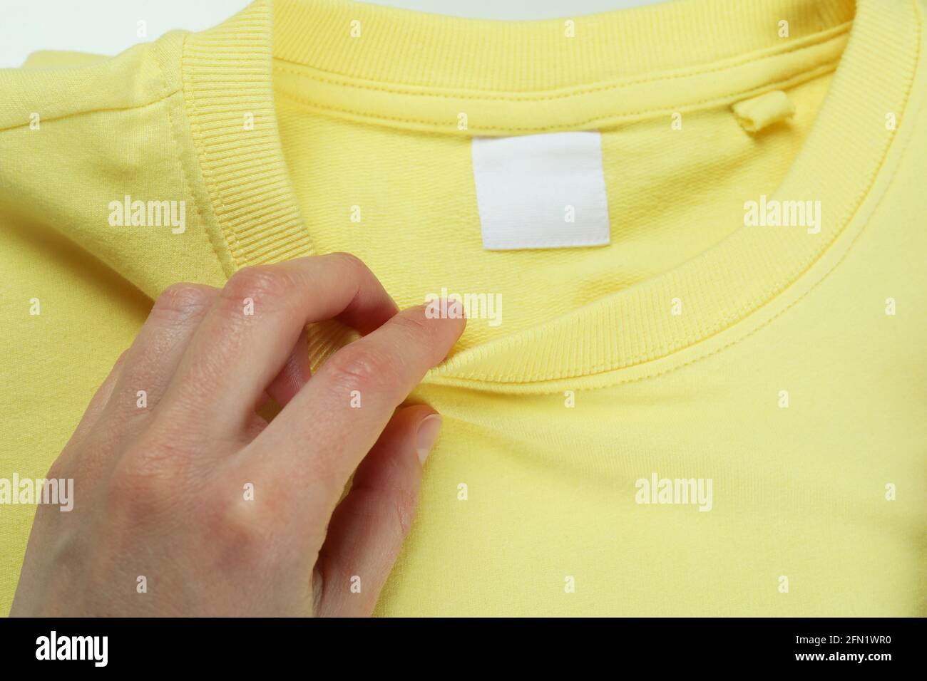 Female hand and yellow sweatshirt, close up Stock Photo