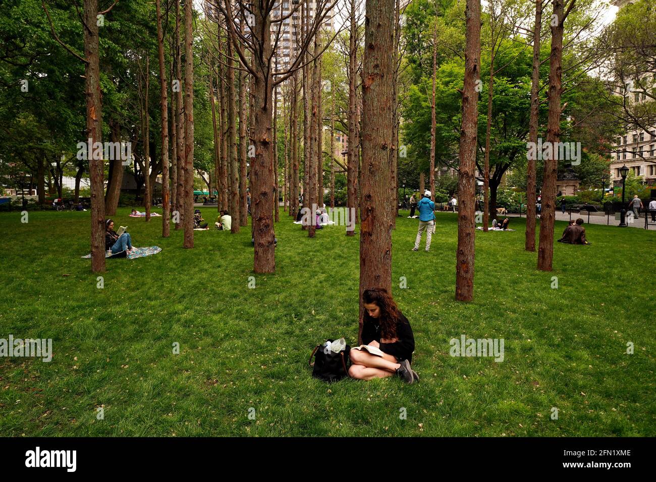 New York City, New York, 13 May 2021: Visitors sit amongst Ghost Forest, a site responsive installation by artist and designer Maya Lin, in New York City’s Madison Square Park on the day of its opening to the public.  The installation consists of forty-nine Atlantic white cedar trees, victims of salt water inundation, is intended to be a both symbol of the devastation of climate change and forest loss around the world, and call to individual action. Credit: Adam Stoltman/Alamy Live News Stock Photo