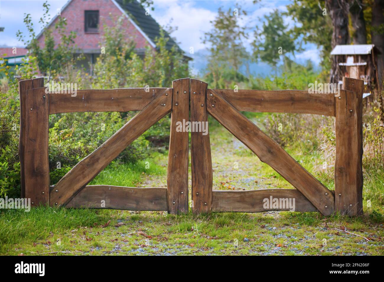Frontal view of a double-leaf entrance gate built from wide wooden boards with a shallow depth of field in a rural setting in daylight Stock Photo