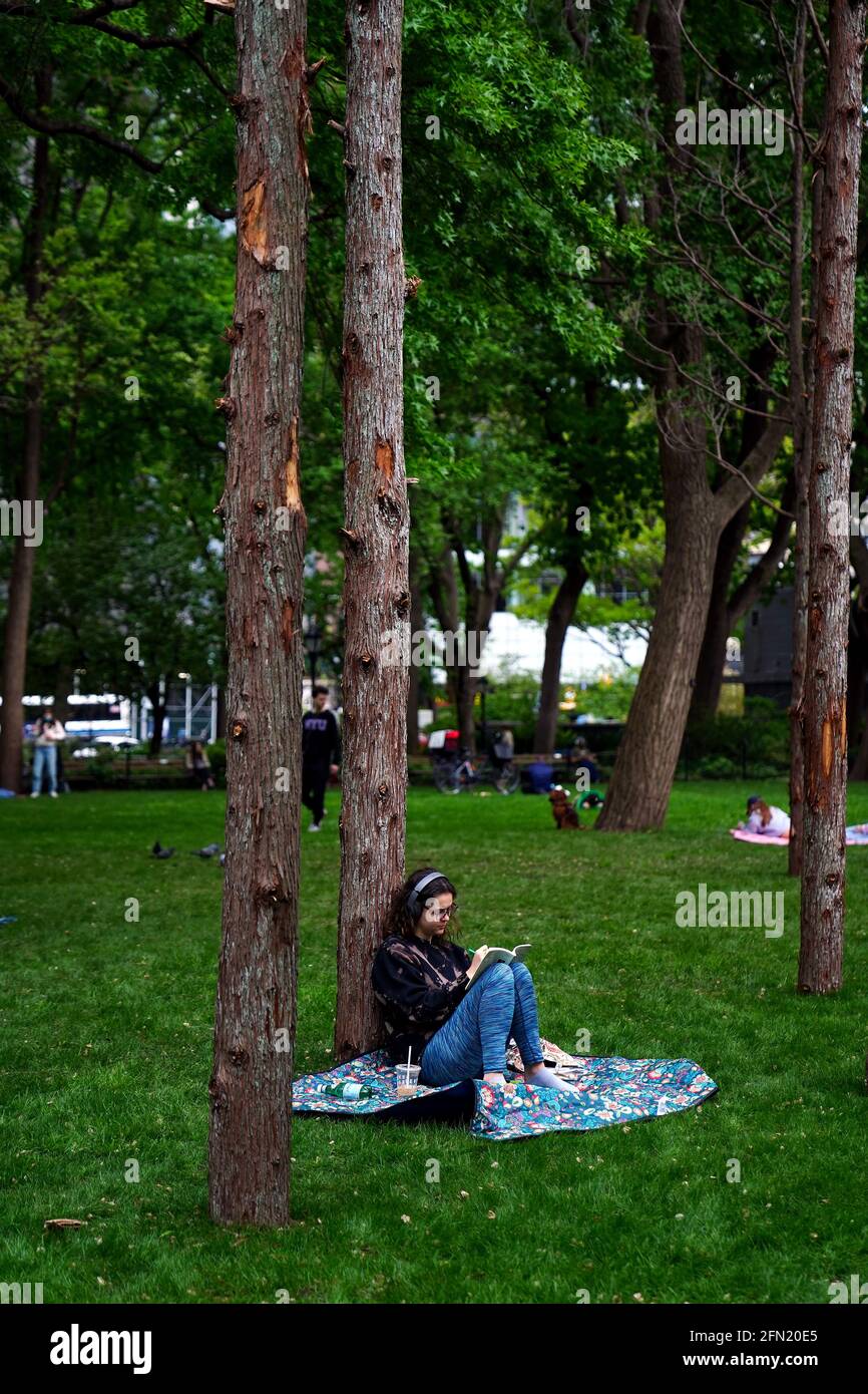 New York City, New York, 13 May 2021: Visitors sit amongst Ghost Forest, a site responsive installation by artist and designer Maya Lin, in New York City’s Madison Square Park on the day of its opening to the public.  The installation consists of forty-nine Atlantic white cedar trees, victims of salt water inundation, is intended to be a both symbol of the devastation of climate change and forest loss around the world, and call to individual action. Credit: Adam Stoltman/Alamy Live News Stock Photo