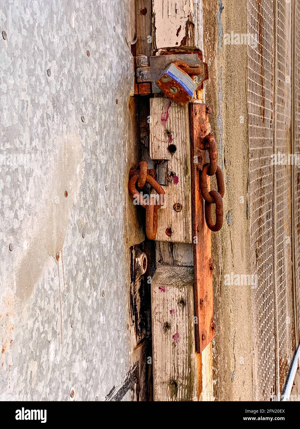 Broken chain and rusted padlock on exterior door Stock Photo