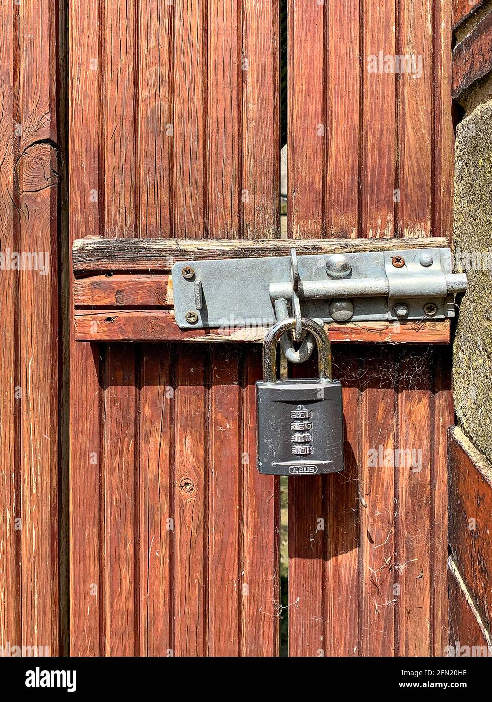 Padlock through bolt on wooden exterior street gate Stock Photo - Alamy