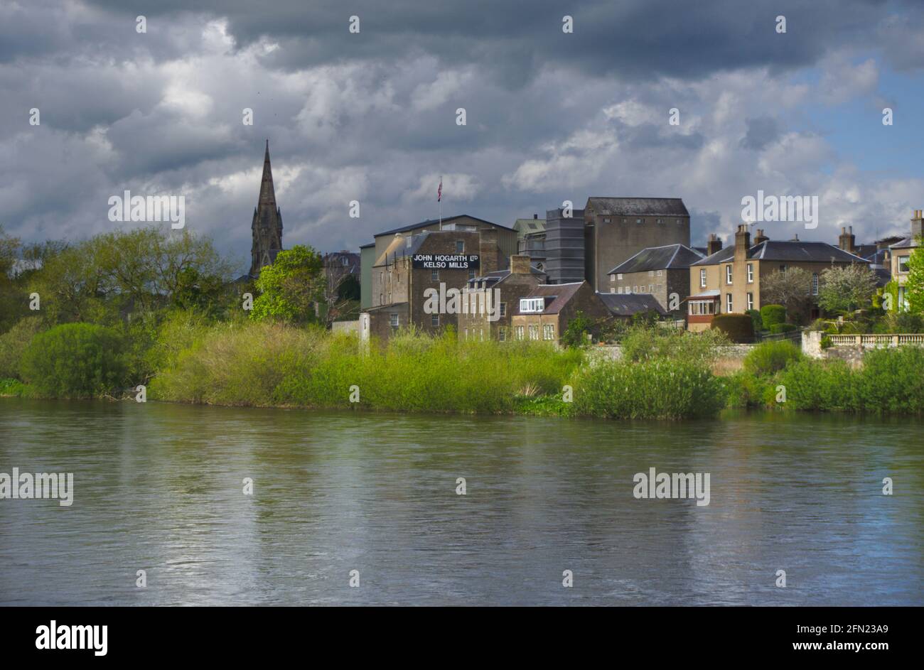 View across the River Tweed of Kelso under a threatening sky, with John Hogarth Ltd Kelso Mills and Kelso North Parish Church in the background. Stock Photo